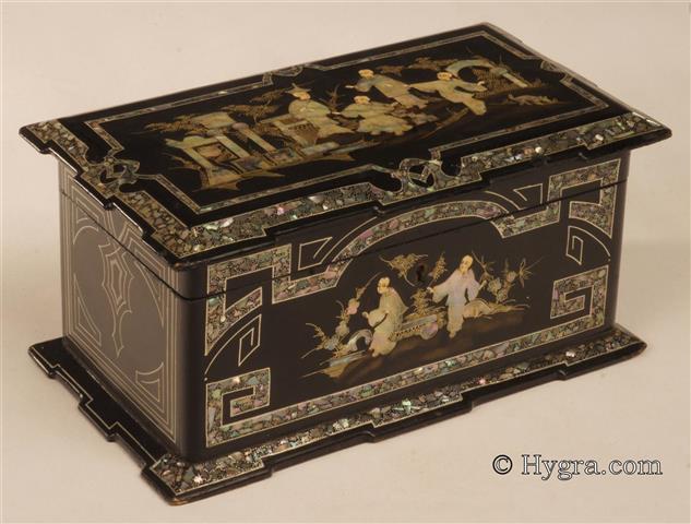 Two compartment tea caddy decorated with Chinoiserie executed in inlaid mother of pearl.  On first sight this looks like papier mch but it is in fact ebonised wood decorated in a manner which suggests papier mch. The top is decorated with figures in a landscape with buildings. This rooted in the Chinoiserie tradition, which reflected both the narratives and drawings brought back from the East by the first explorer/traders. One feature of the orient which captured the imagination of the Europeans was the extensive ornamental gardens complete with lakes and small islands, enjoyed by the cultural elite.  Enlarge Picture
